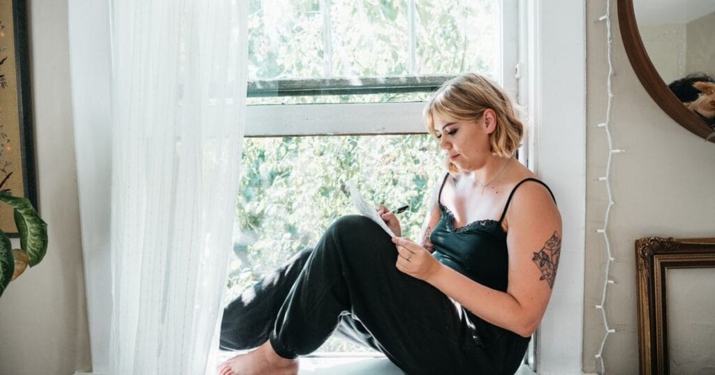 Mujer escribiendo en un cuaderno sentada junto a la ventana: cómo saber si tienes un TCA